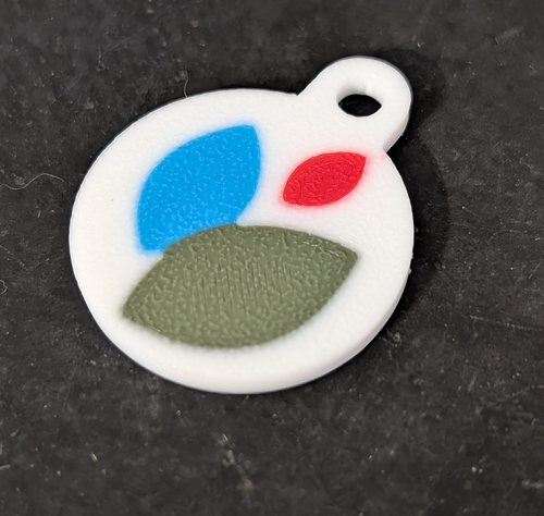 Un jeton de caddie imprimé en 3D, bicolore, aux couleurs d'un établissement.